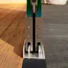 Steellook glazen schuifwand met 2 rails met vooraanzicht van het einde van de rails, houten vloer en stenen vloeren aan de 2 kanten.