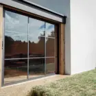 Steellook glazen schuifwand met 3 rails met witte muur ernaast en nette tuin ervoor
