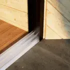 Steellook glazen schuifwand met 3 rails met houten muur ernaast en 2 verschillende vloeren aan beide kanten