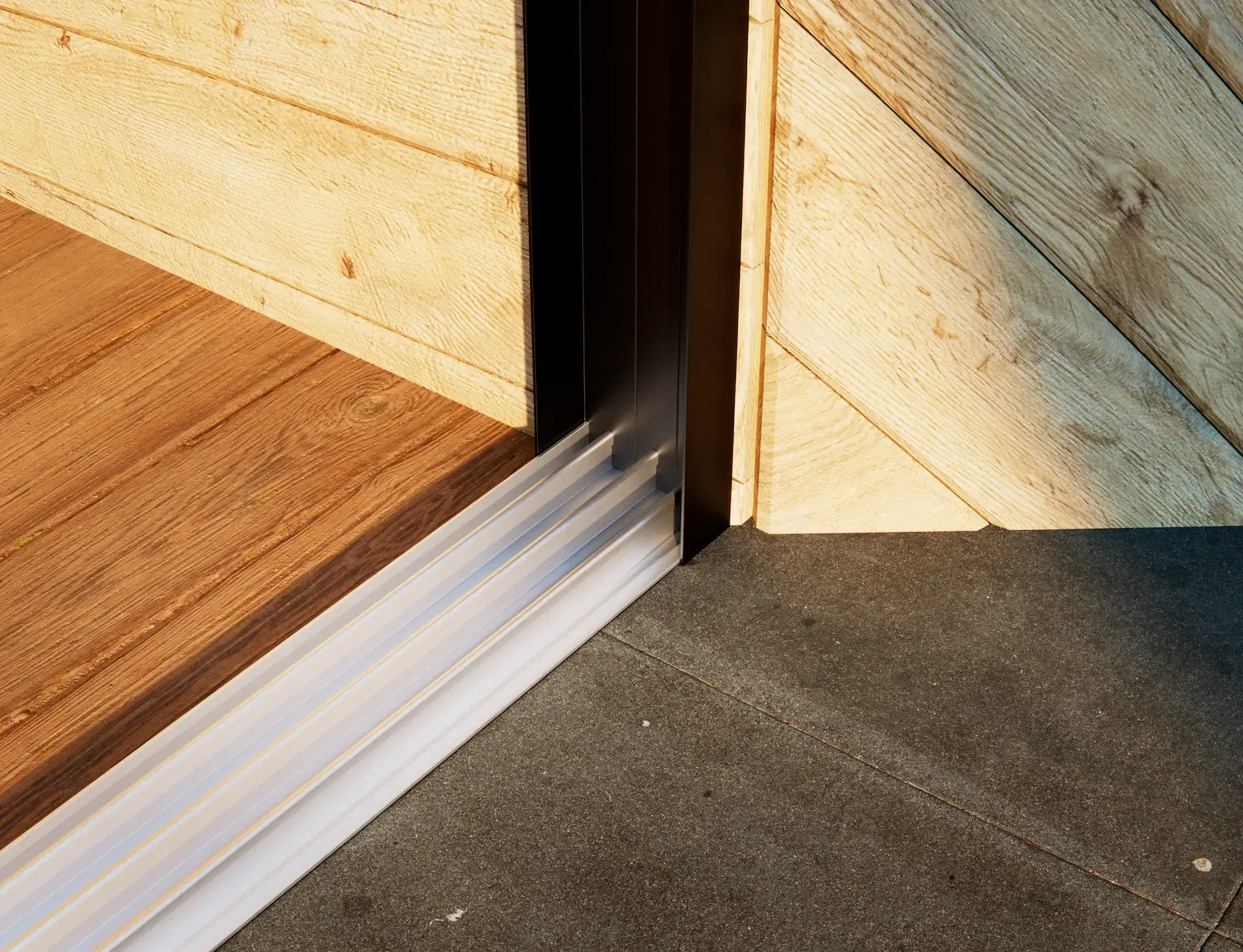 Steellook glazen schuifwand met 3 rails met houten muur ernaast en 2 verschillende vloeren aan beide kanten