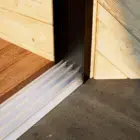 Steellook glazen schuifwand met 4 rails, met houten muren en verschillende vloeren aan beide kanten van de schuifwanden