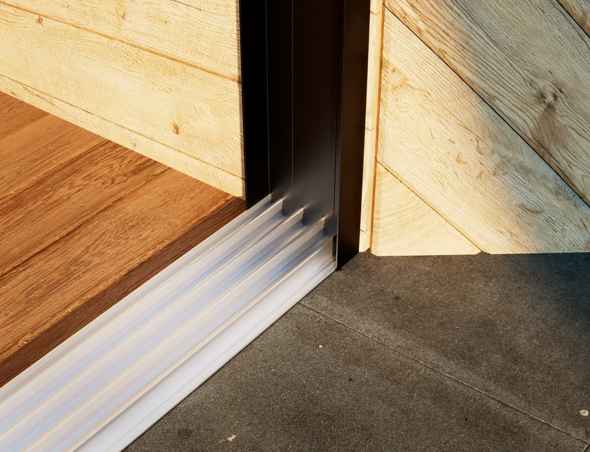 Steellook glazen schuifwand met 4 rails, met houten muren en verschillende vloeren aan beide kanten van de schuifwanden