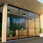 Steellook glazen schuifwand met 4 rails, houten muren en plafond. Met planten ingericht en buitenlucht zichtbaar