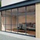 Steellook glazen schuifwand met 5 rails, nette staalbalken erdoor, bank ingericht aan de binnenkant.