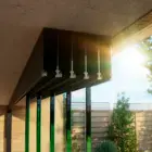 Steellook glazen schuifwand met 5 rails, bovenrails zichtbaar en tuin ook zichtbaar, in de achtergond, closeup